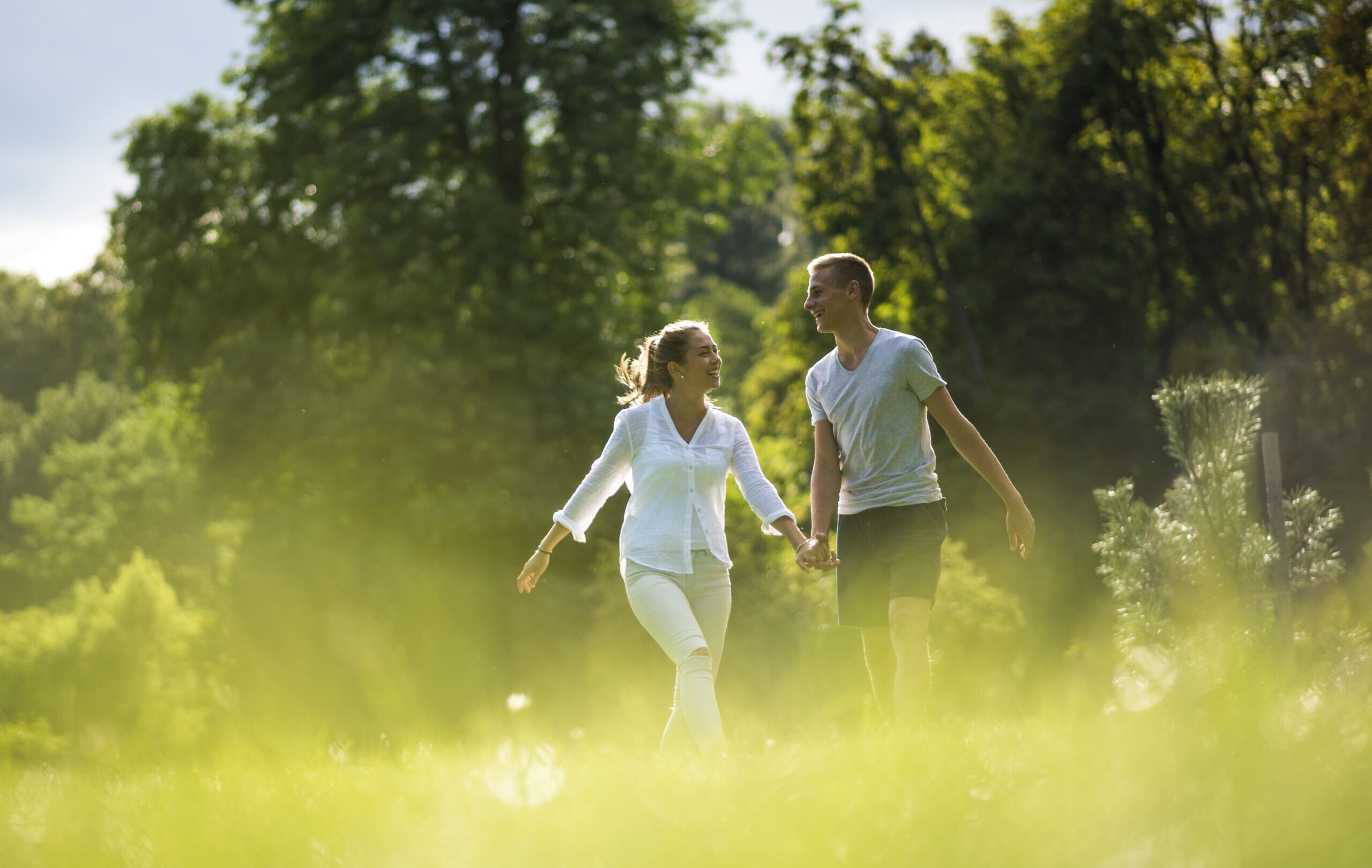 ein Paar, das sich an den Händen hält und über ein Feld läuft